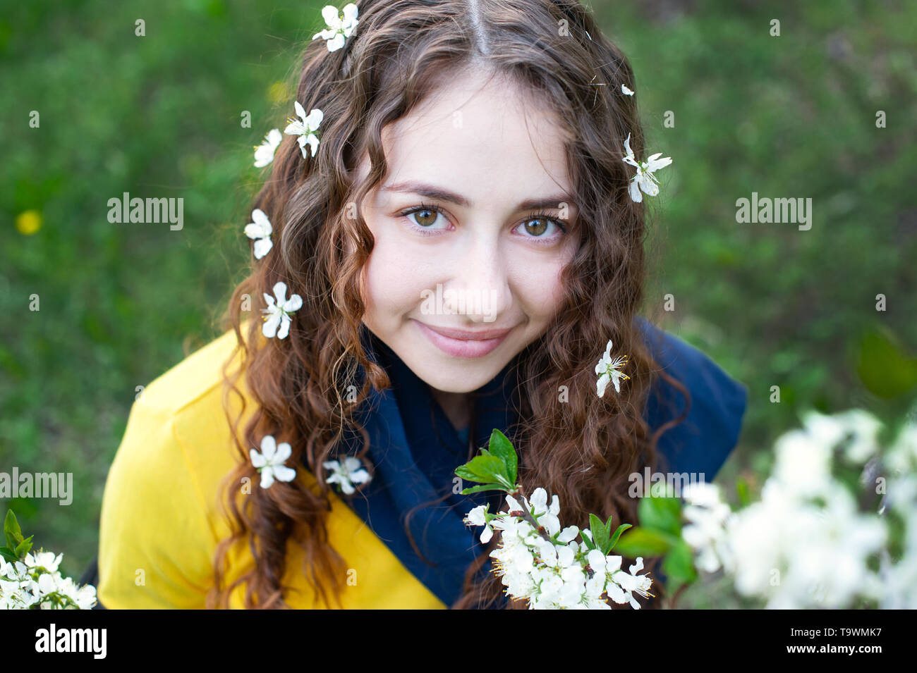 Happy young woman enjoying smell flowers over spring garden background Stock Photo