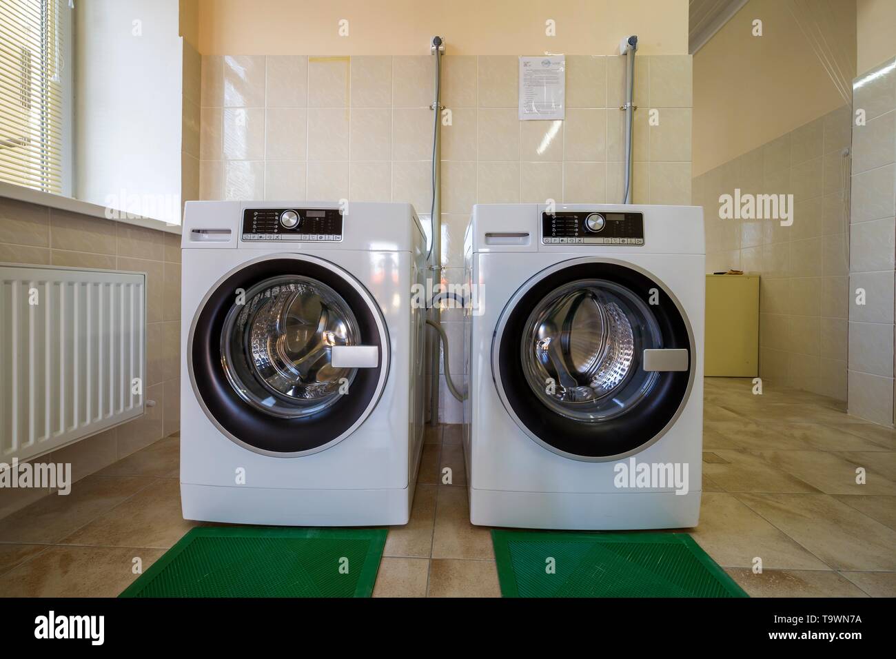 Modern New Industrial Washing Machines In Clean Tiled Bathroom Or
