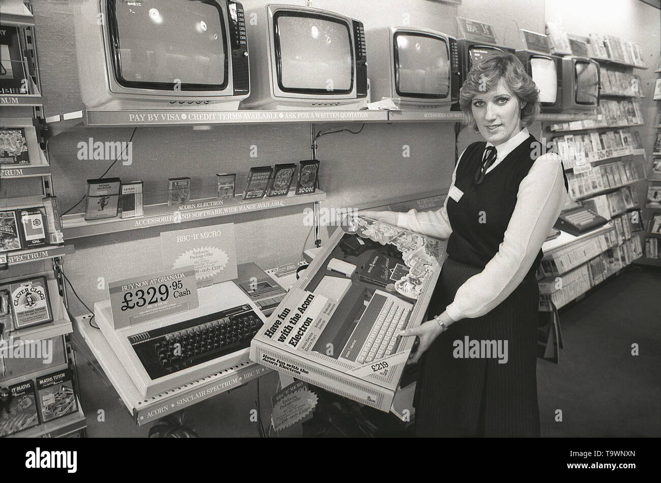 1985, historical, home electronic equipment inside a Granada TV retail shop, a female shop assistant shows the new Acorn Electron home computer, England, UK. Stock Photo