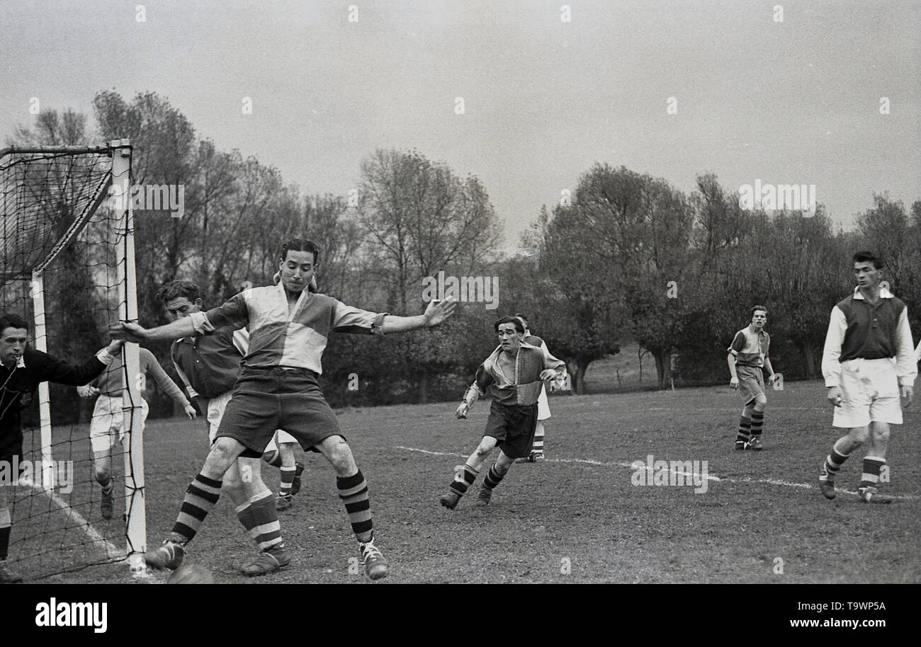 1950s, historical, amateur football match, picture shows players in the kit of the era, long, baggy shorts, long-sleeved shirts with collars and ankle-high boots competing for the ball in the goalmouth, England, UK. Stock Photo