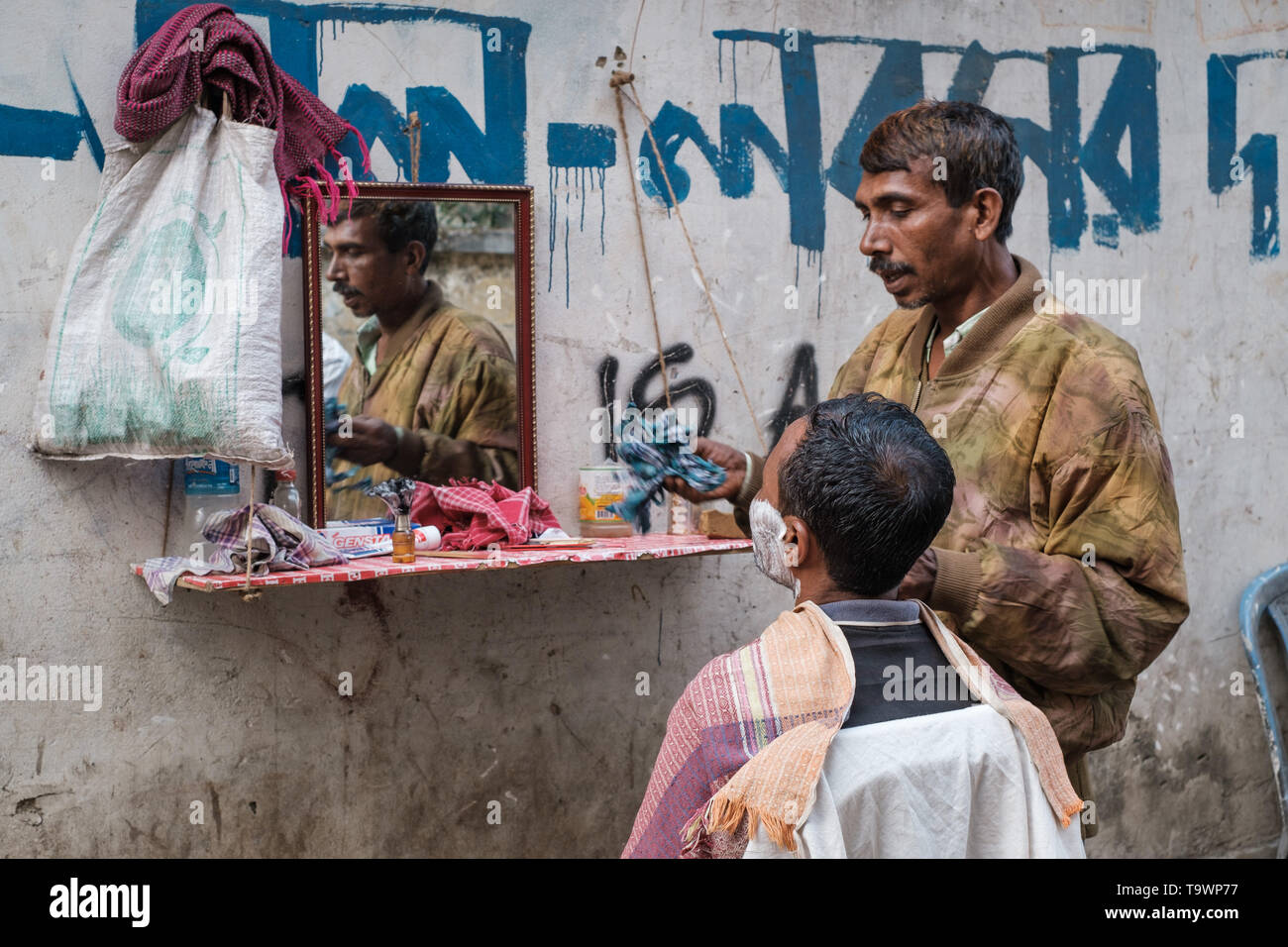 Street barber is seen as he shaves customer in his barber shop in Dhaka