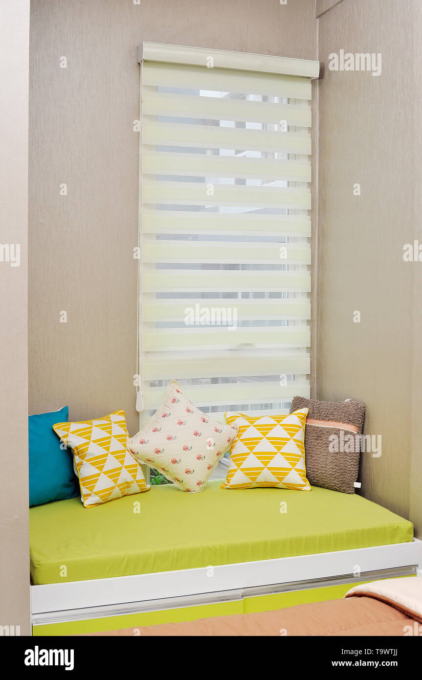 modern minimalist interior small sofa with cushion near windows in small apartment Stock Photo