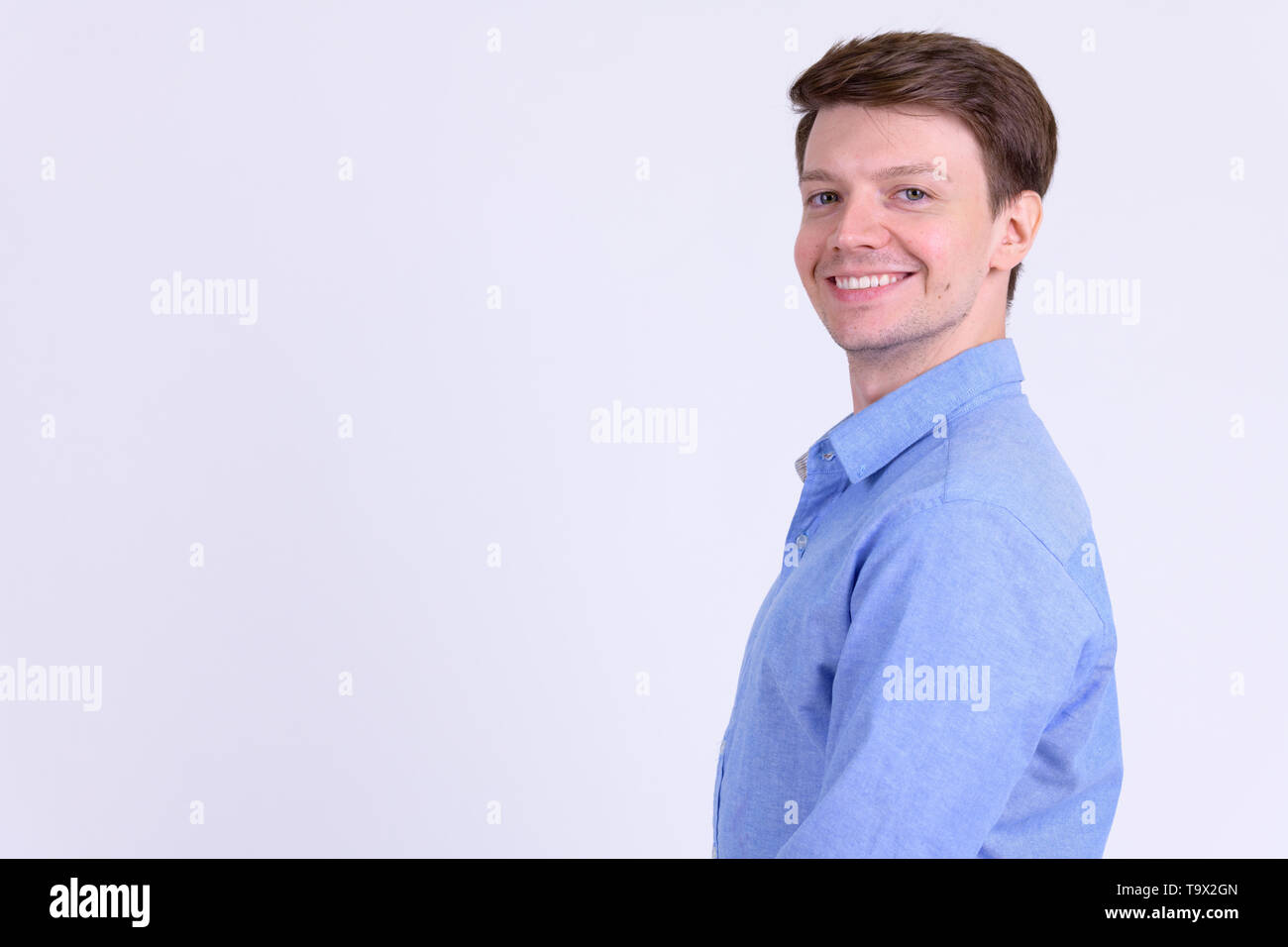 Profile view of young happy businessman smiling and looking at camera ...