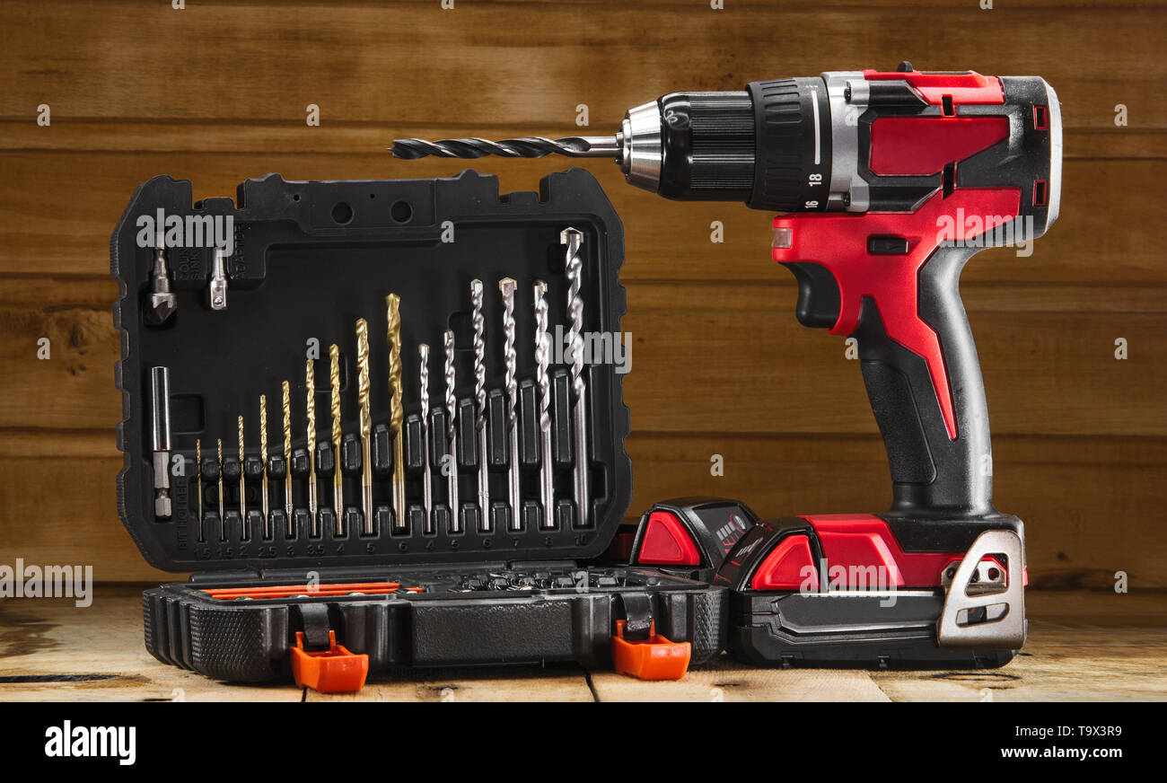 Cordless drill driver in red with rubberized handle in profile with drill bits set Stock Photo