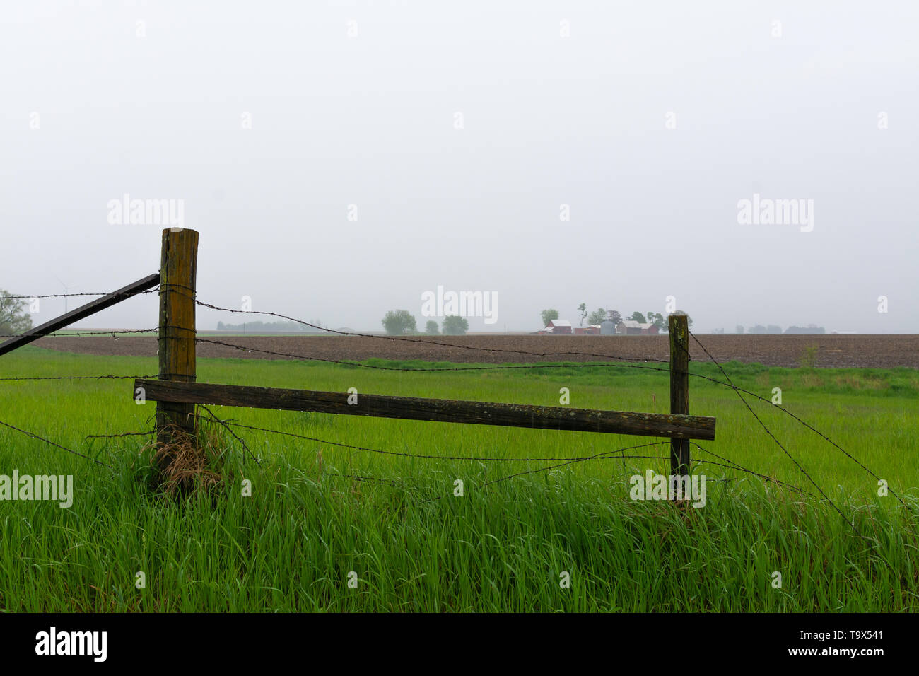 Old wooden fence with farmland in the background as Spring rain falls ...