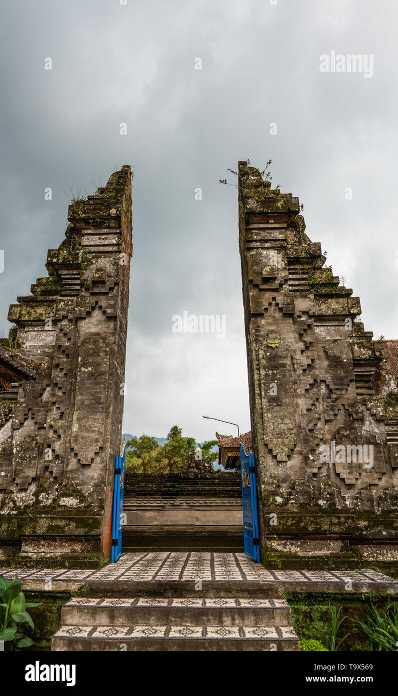 Bali, Indonesia - February 25, 2019: Ulun Danu Beratan Temple in Bedoegoel. Brown stone split gate or Candi Bentar gives access to sanctuary. Blue met Stock Photo