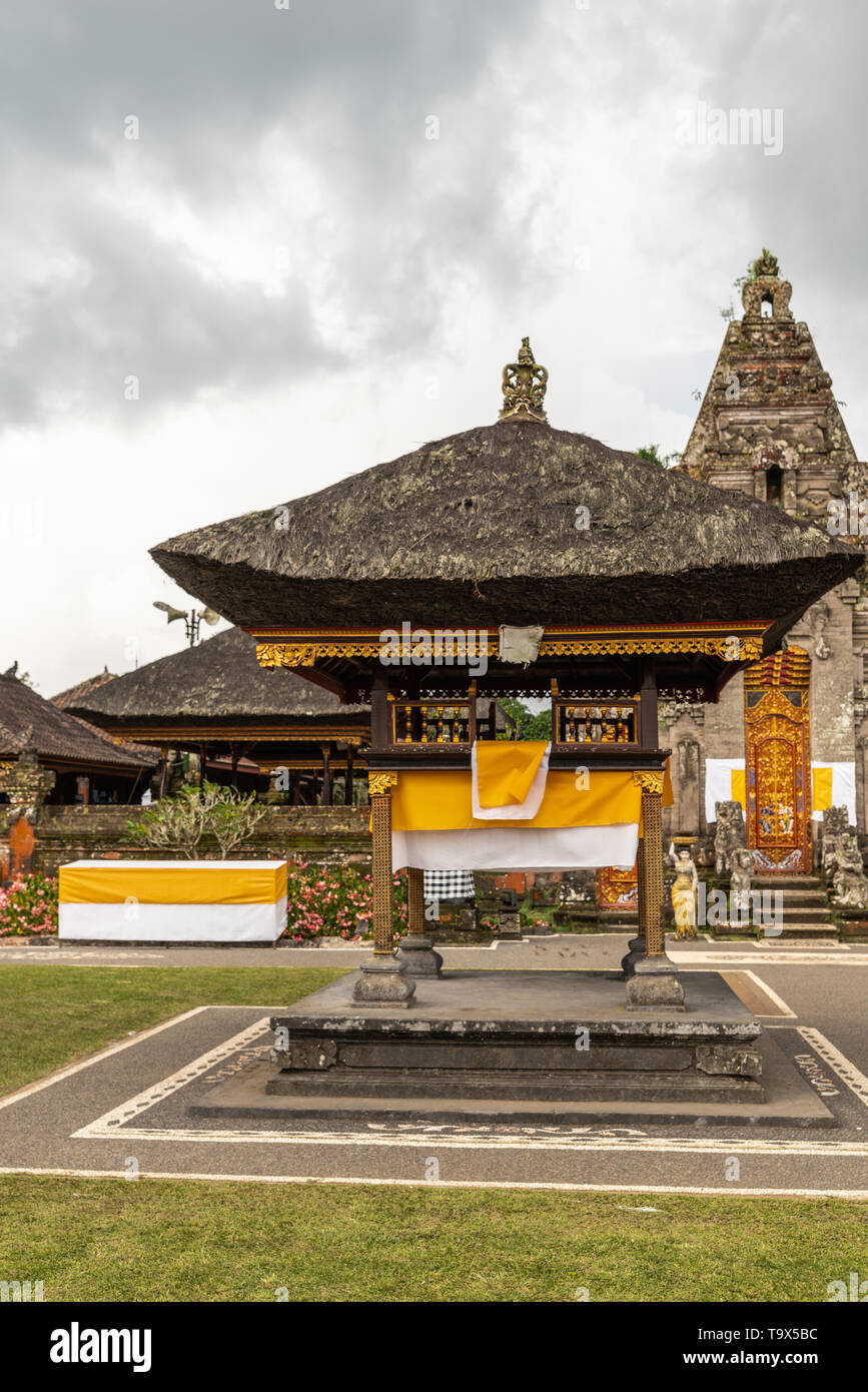 Bali, Indonesia - February 25, 2019: Ulun Danu Beratan Temple in Bedoegoel. Reet covered golden Gamelan Pavilion in green garden, built on brown stone Stock Photo