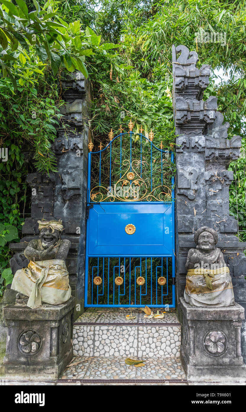 Bali, Indonesia - February 25, 2019: Ulun Danu Beratan Temple in Bedoegoel. Gray stone split gate or Candi Bentar gives access to green sanctuary. Blu Stock Photo
