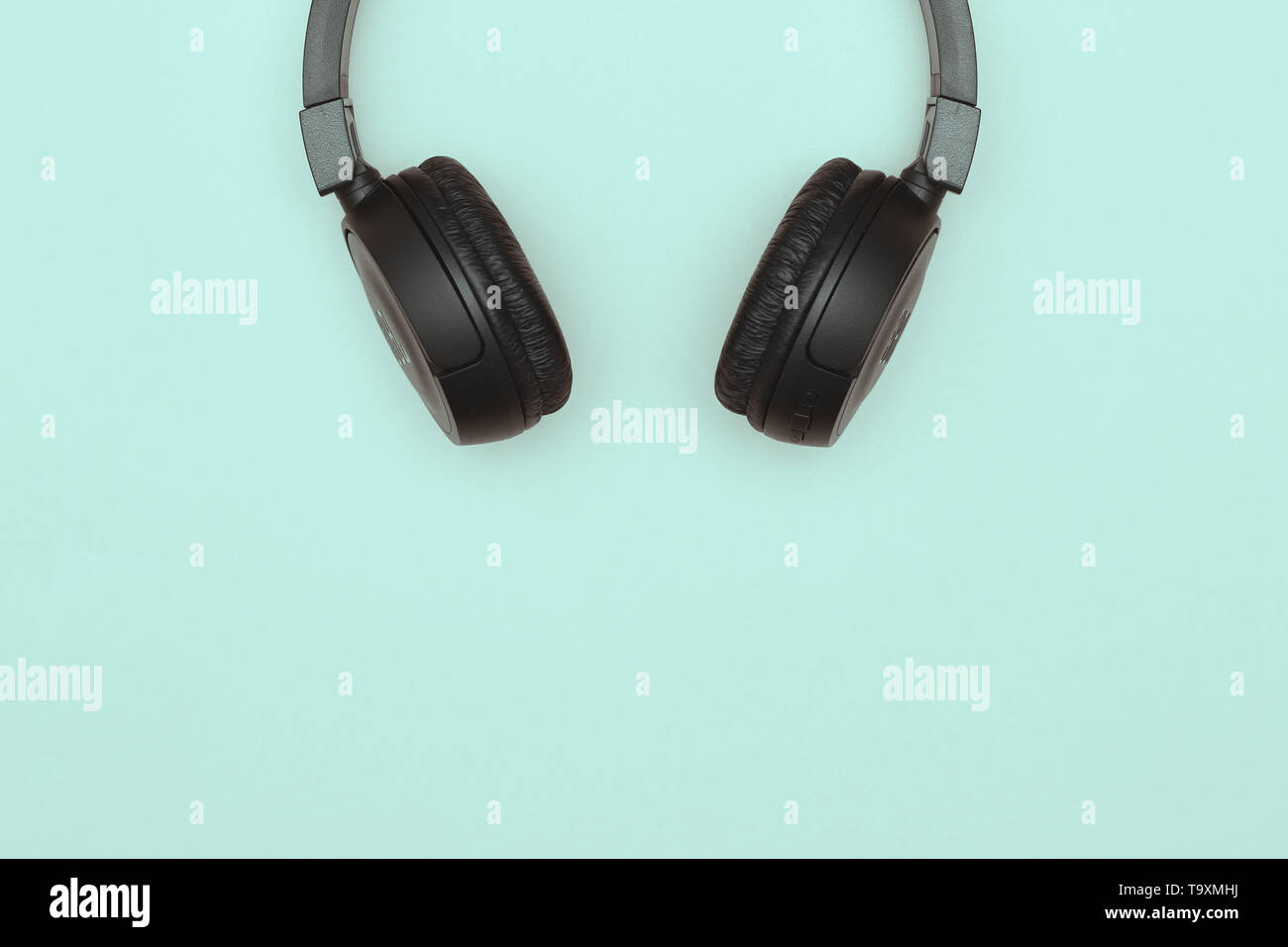 Modern black wireless headphones on a blue background. The concept of music and fashion. Minimalism. copy space. space for text Stock Photo