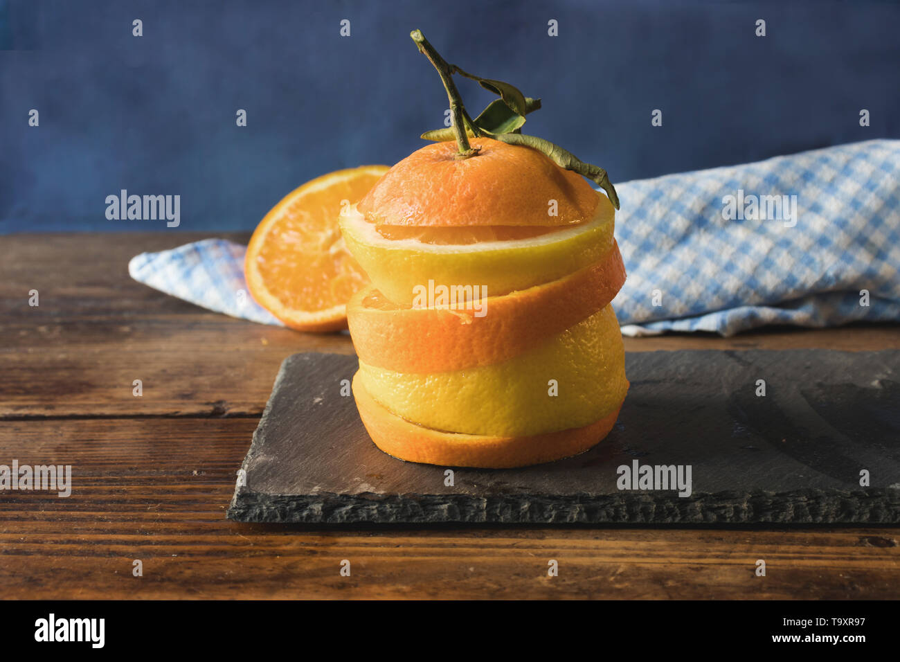 Sliced lemons and oranges stacked, on a slate table on an old wooden table Stock Photo