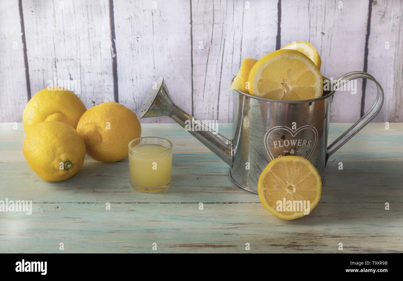 Still life of cut lemons on a metal watering can and lemon juice. Light