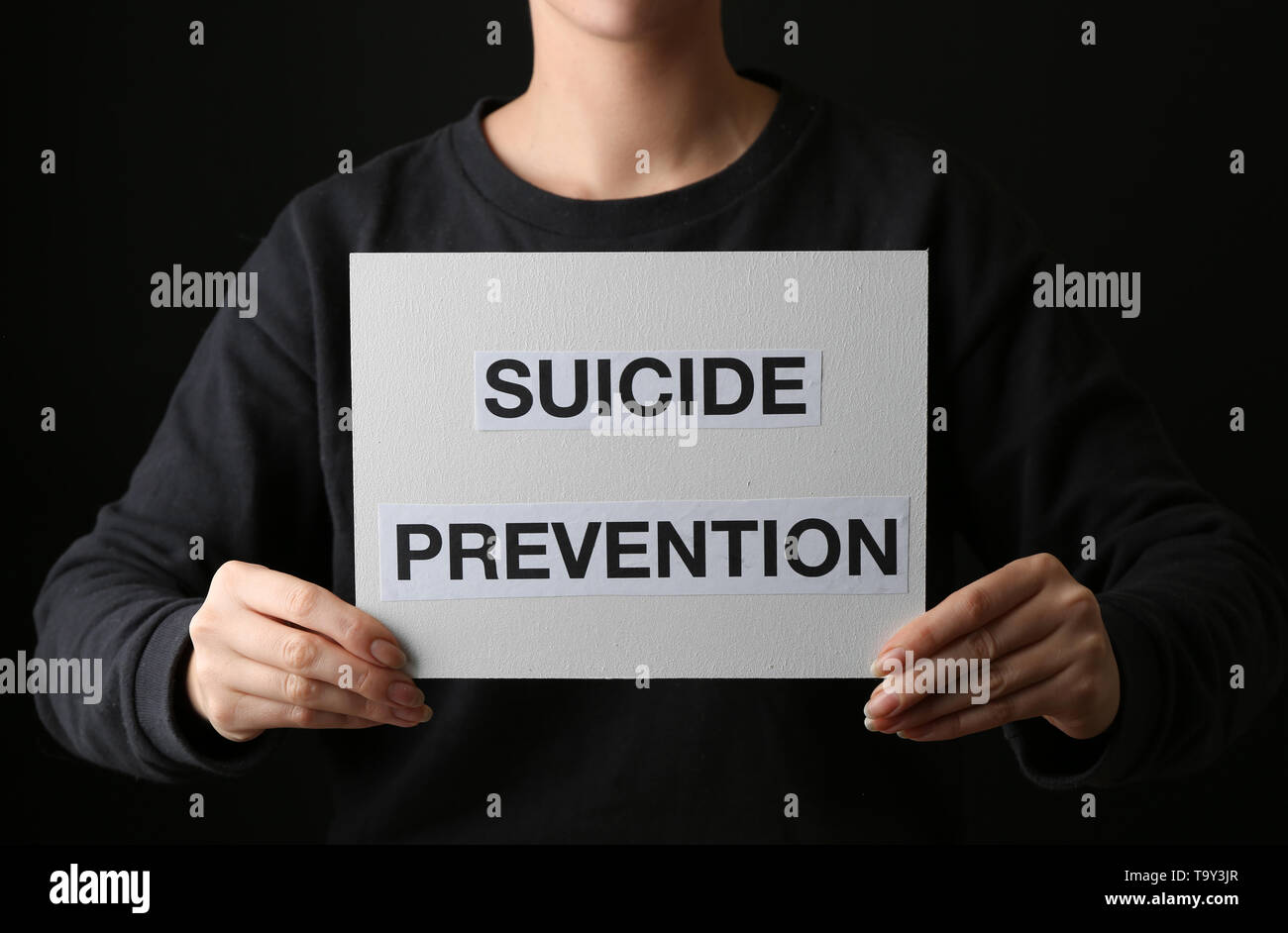 Woman holding paper sheet with text SUICIDE PREVENTION on dark ...
