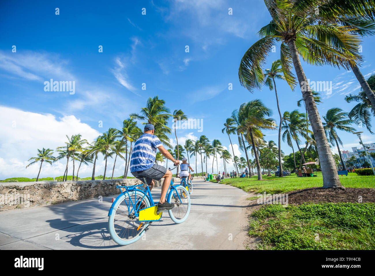 Tourists ride bicycles along the beachfront promenade in Lummus Park adjacent to historic Ocean Drive in South Beach, Miami, Florida, USA Stock Photo