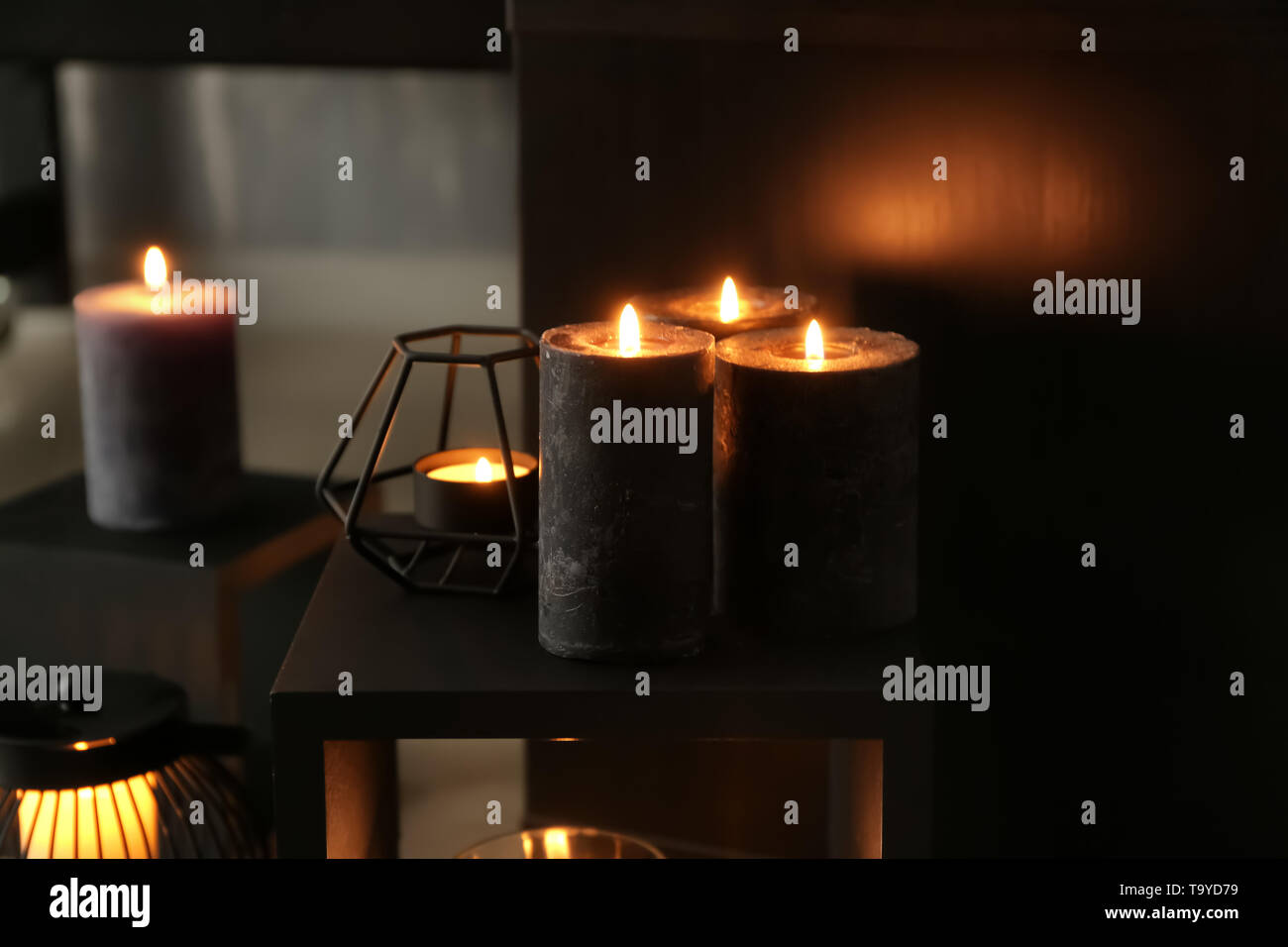 Beautiful burning candles on shelf in room Stock Photo Alamy