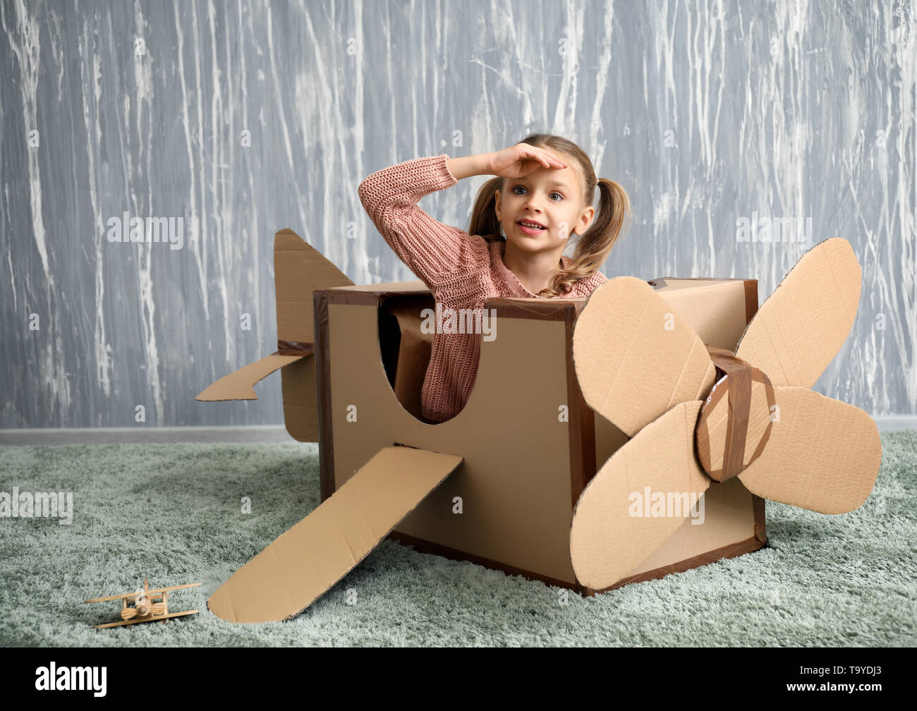 Little girl playing with cardboard airplane in room Stock Photo - Alamy