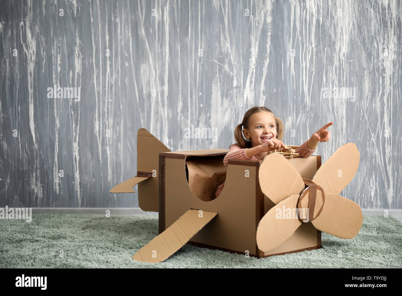 Little girl playing with cardboard airplane in room Stock Photo - Alamy