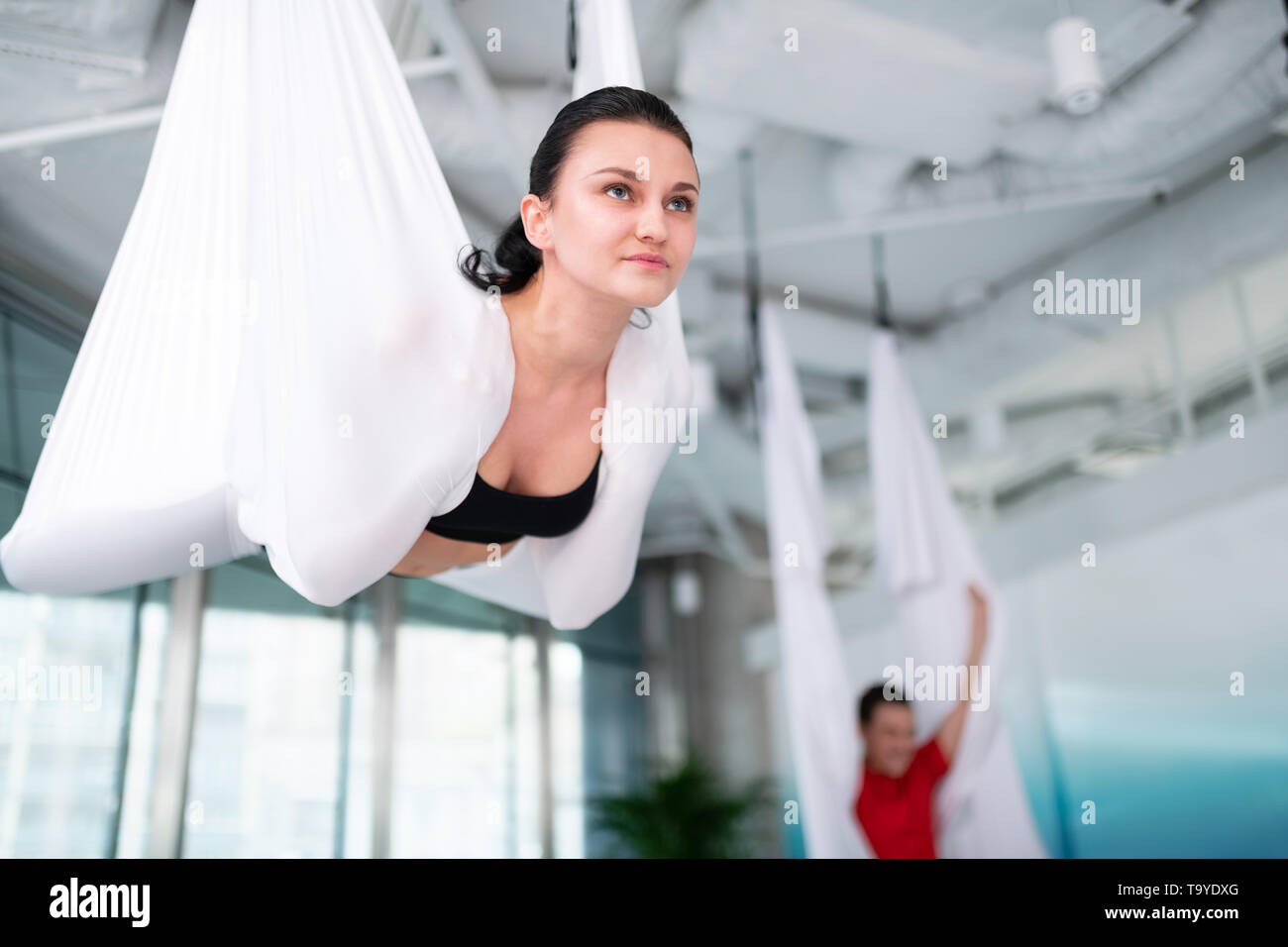 Dark-haired woman wearing black top trying aerial yoga Stock Photo