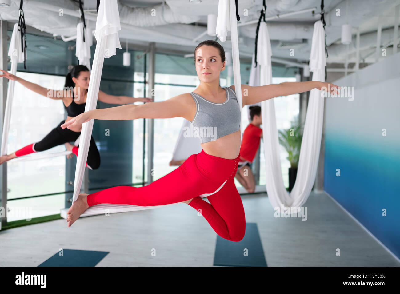 Businesswoman in red leggings attending aerial yoga course Stock Photo