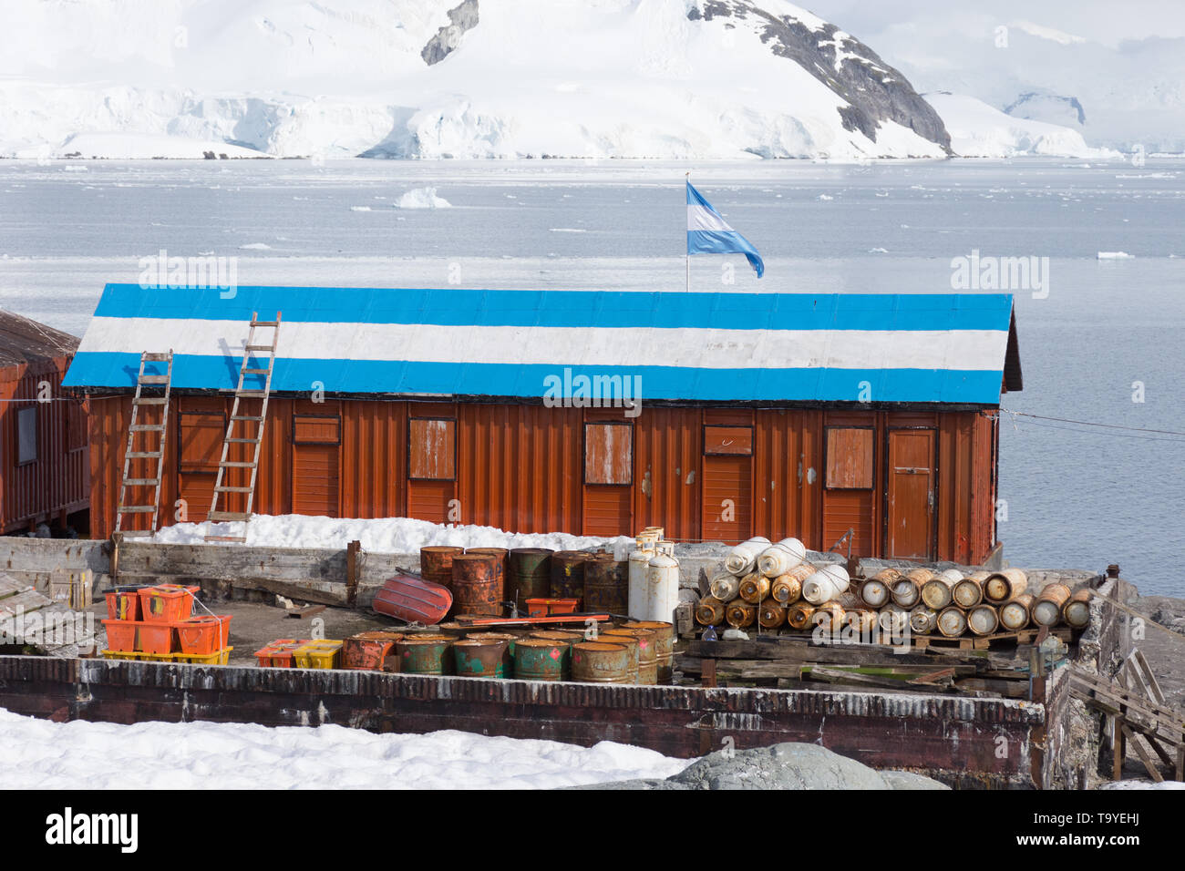 Close up of a rust colored metal building in Camp Brown in Antarctica. The research station has an Argentinian flag painted on the roof. Stock Photo