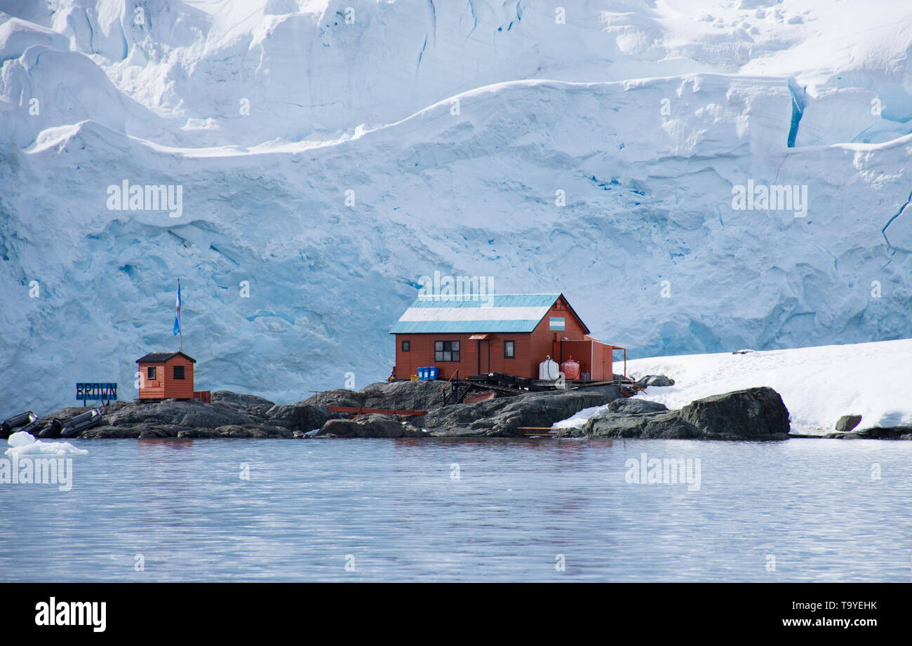 Rust colored metal buildings in Argentina's Camp Brown research base in Antarctica with blue and white snow in the background. Stock Photo