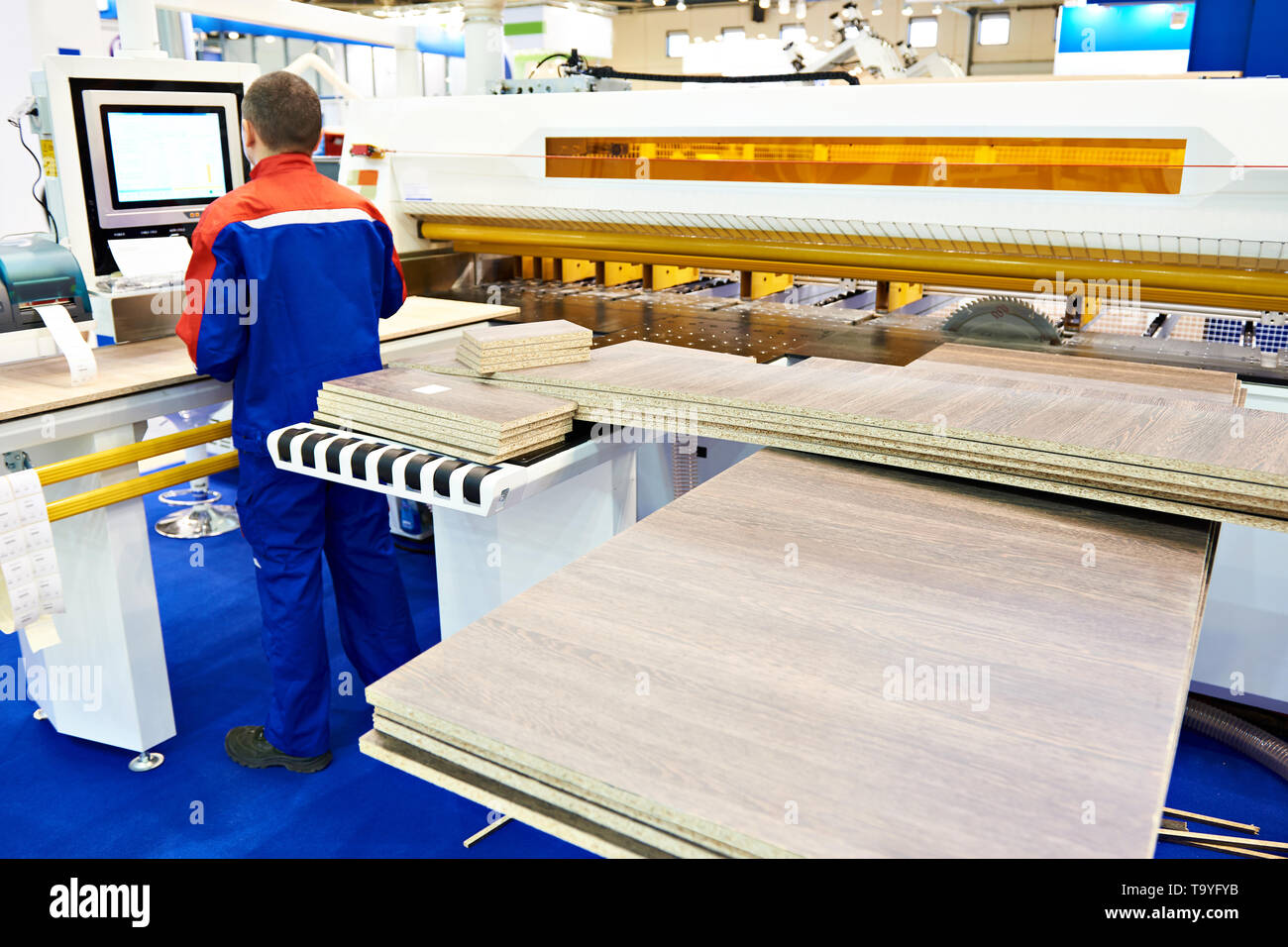 Operator worker near panel saw machine and wooden furniture details Stock Photo