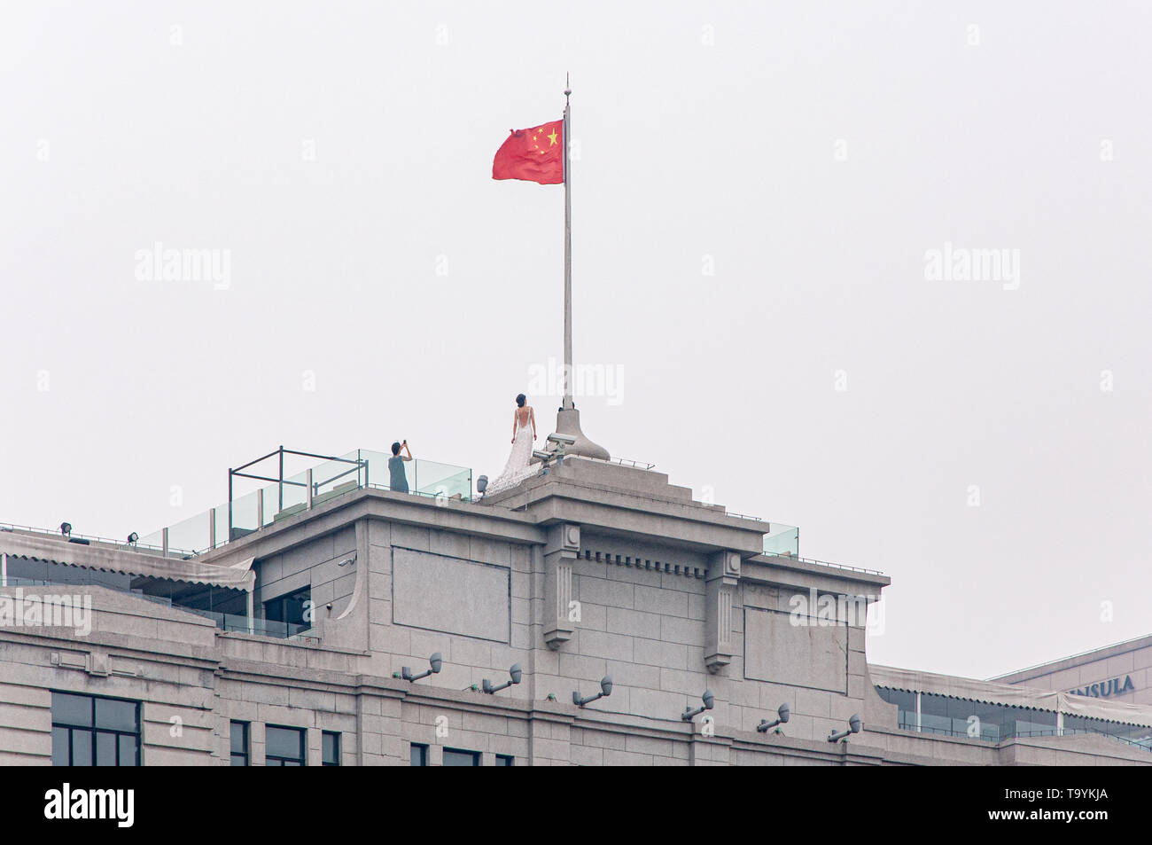 SHANGHAI, CHINA - JUN 2013: Newlyweds make wedding photos on the background of the national flag of China on the roof of the government building in Sh Stock Photo