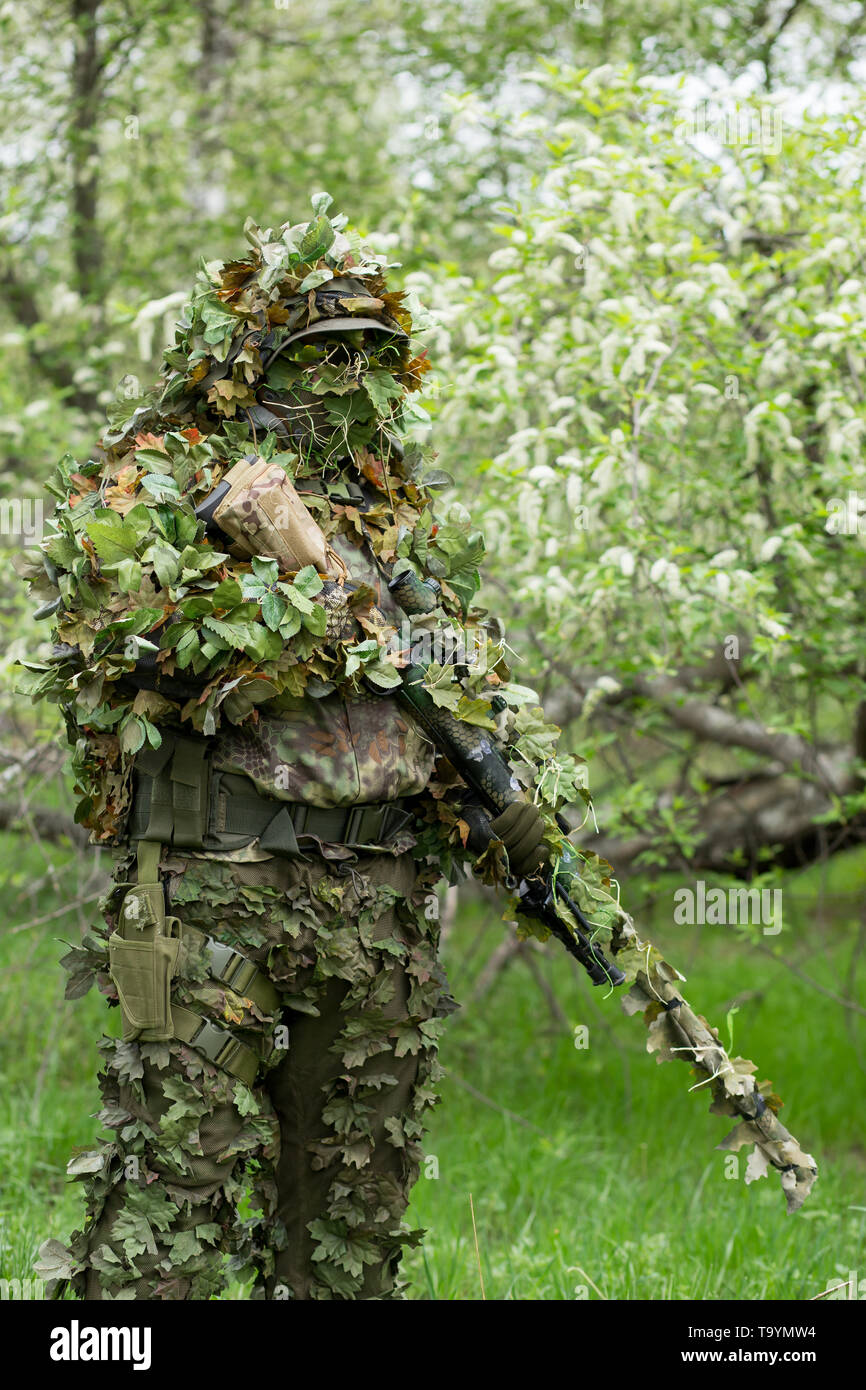 Portrait of a military man in camouflage clothes with a weapon on his hand in nature in the summer. Army, military, airsoft, hobby, game concept Stock Photo