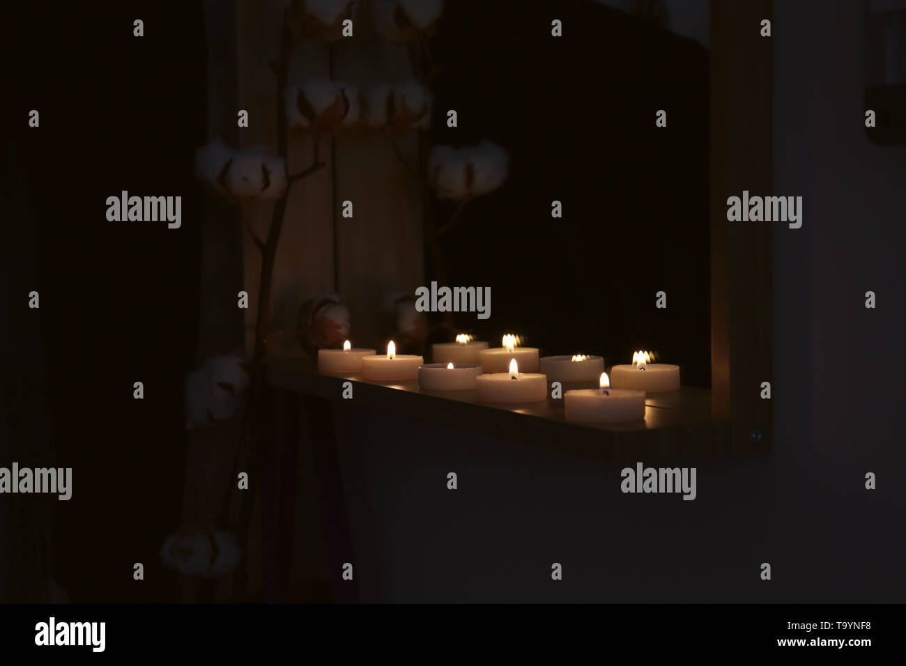 Many burning candles on shelf in dark room Stock Photo Alamy