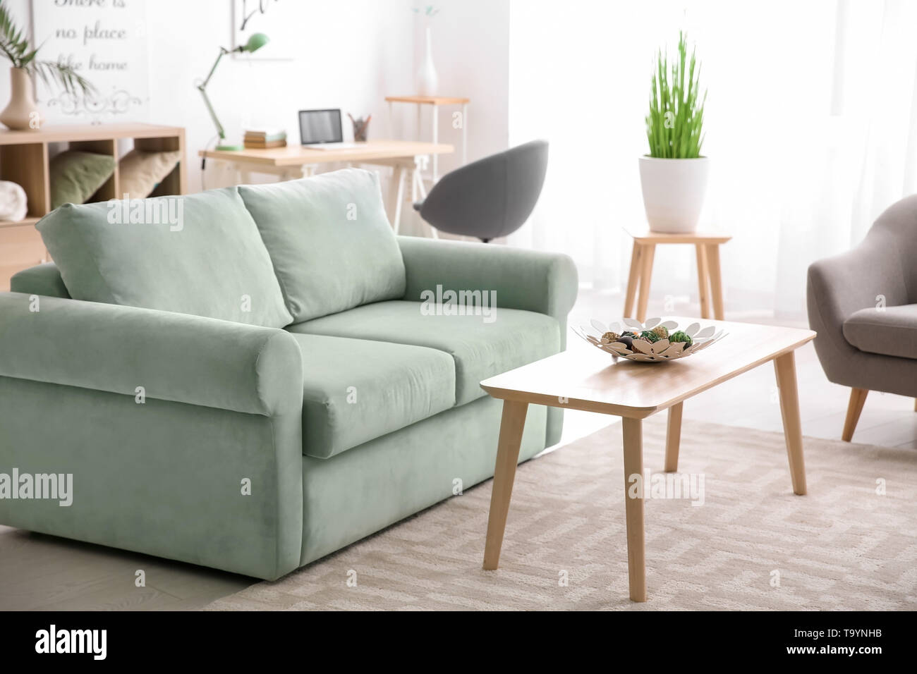 Stylish interior of living room with comfortable sofa and wooden table ...