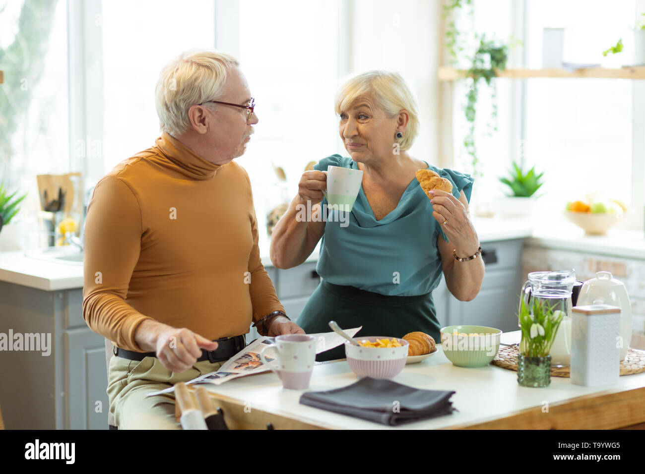 Cheerful couple having breakfast and chatting at the kitchen table Stock Photo