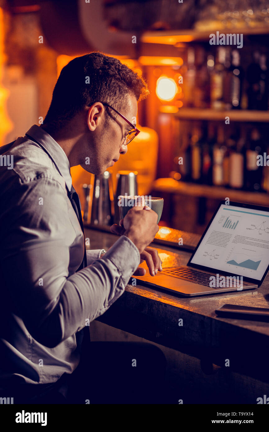 Freelancer drinking coffee and working sitting in his restaurant Stock Photo