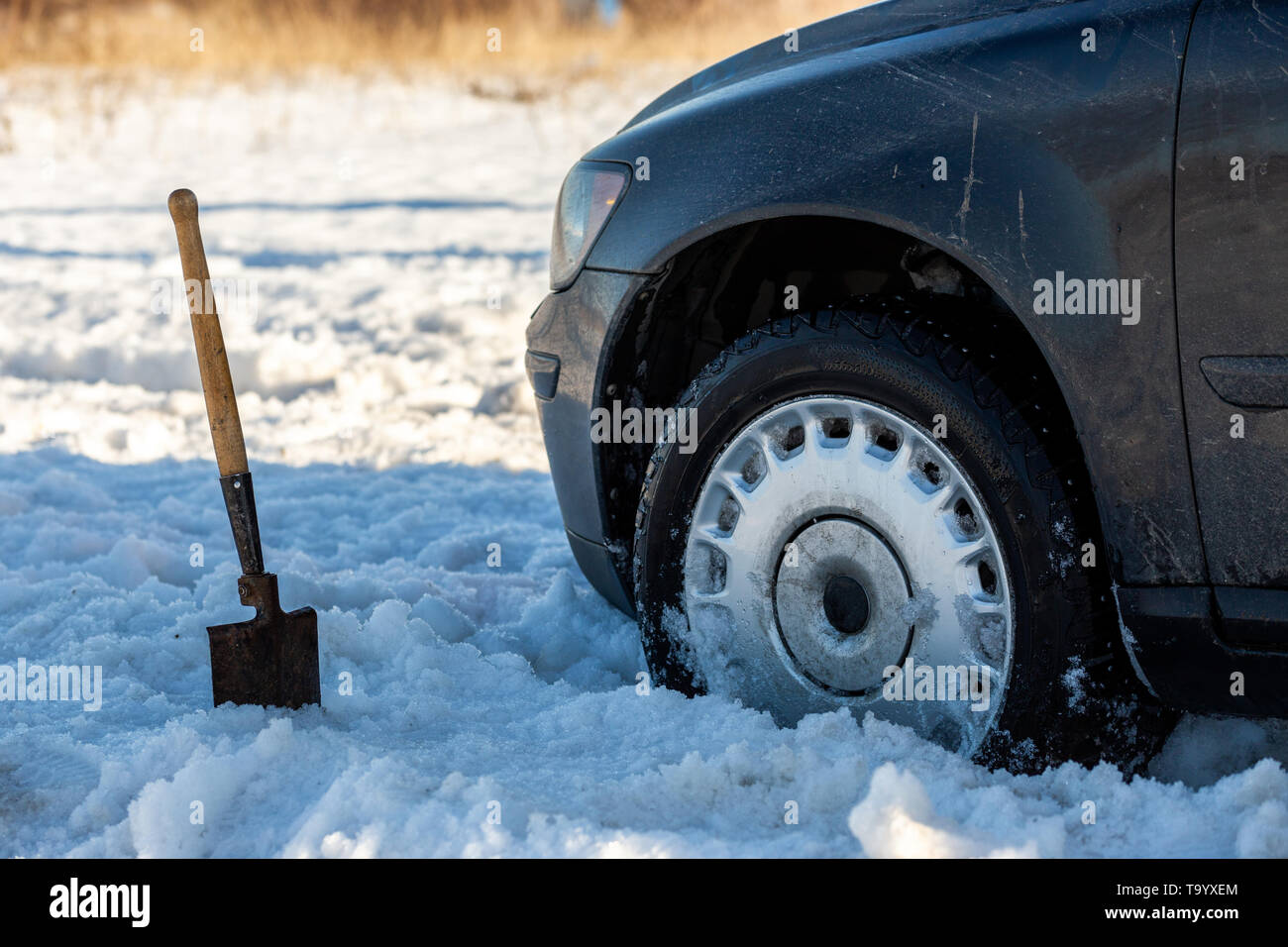 car stuck in snow offroad at daylight with shovel and selective focus. Stock Photo