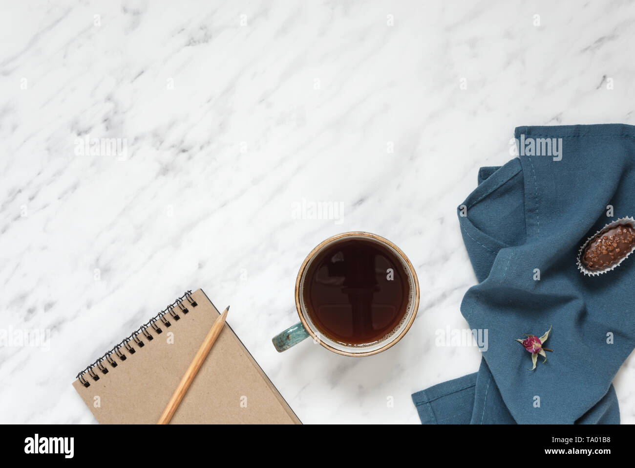 Morning composition with cup of black coffee, blue napkin and notebook on a marble surface, with space for text, top view Stock Photo