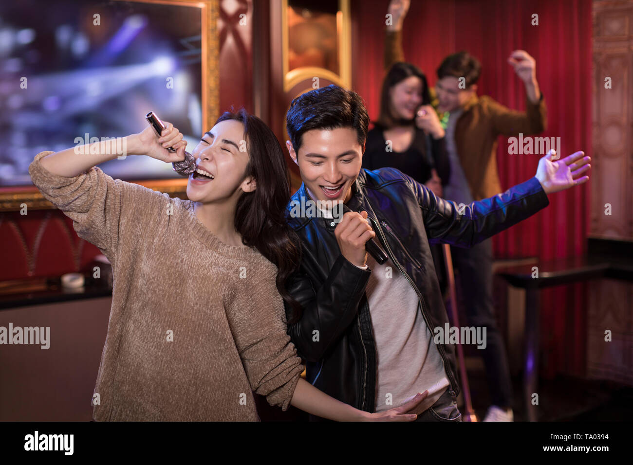 Happy young couple singing karaoke in Stock Photo Alamy