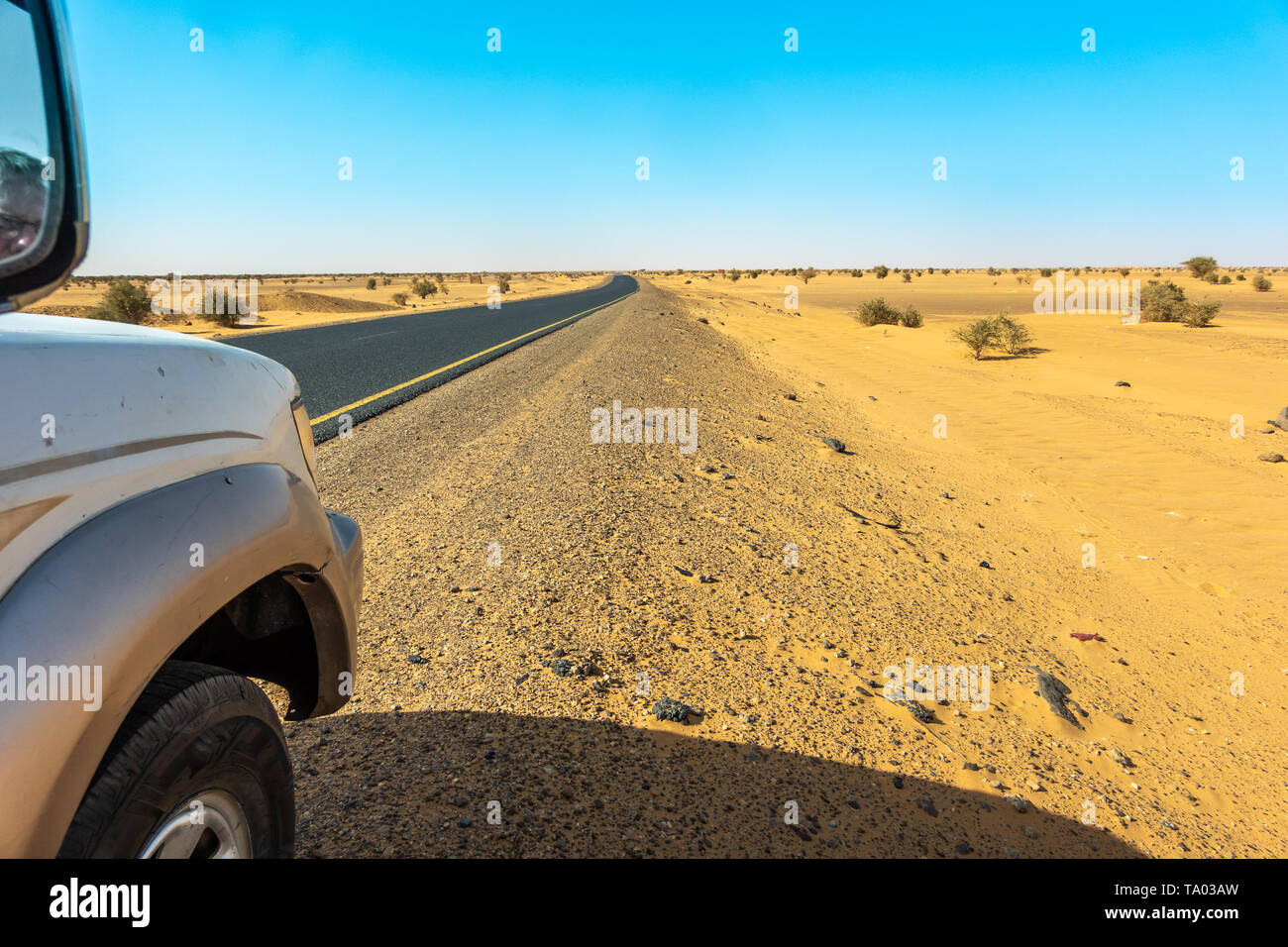 Driving on the grey asphalt road throw the sandy sahara of sudan, africa Stock Photo