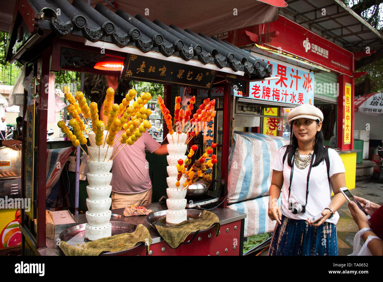 Chinese people and foreigner travelers select and buy dessert fruit coating sugar in local shop at night street market at Shantou or Swatow on May 7,  Stock Photo