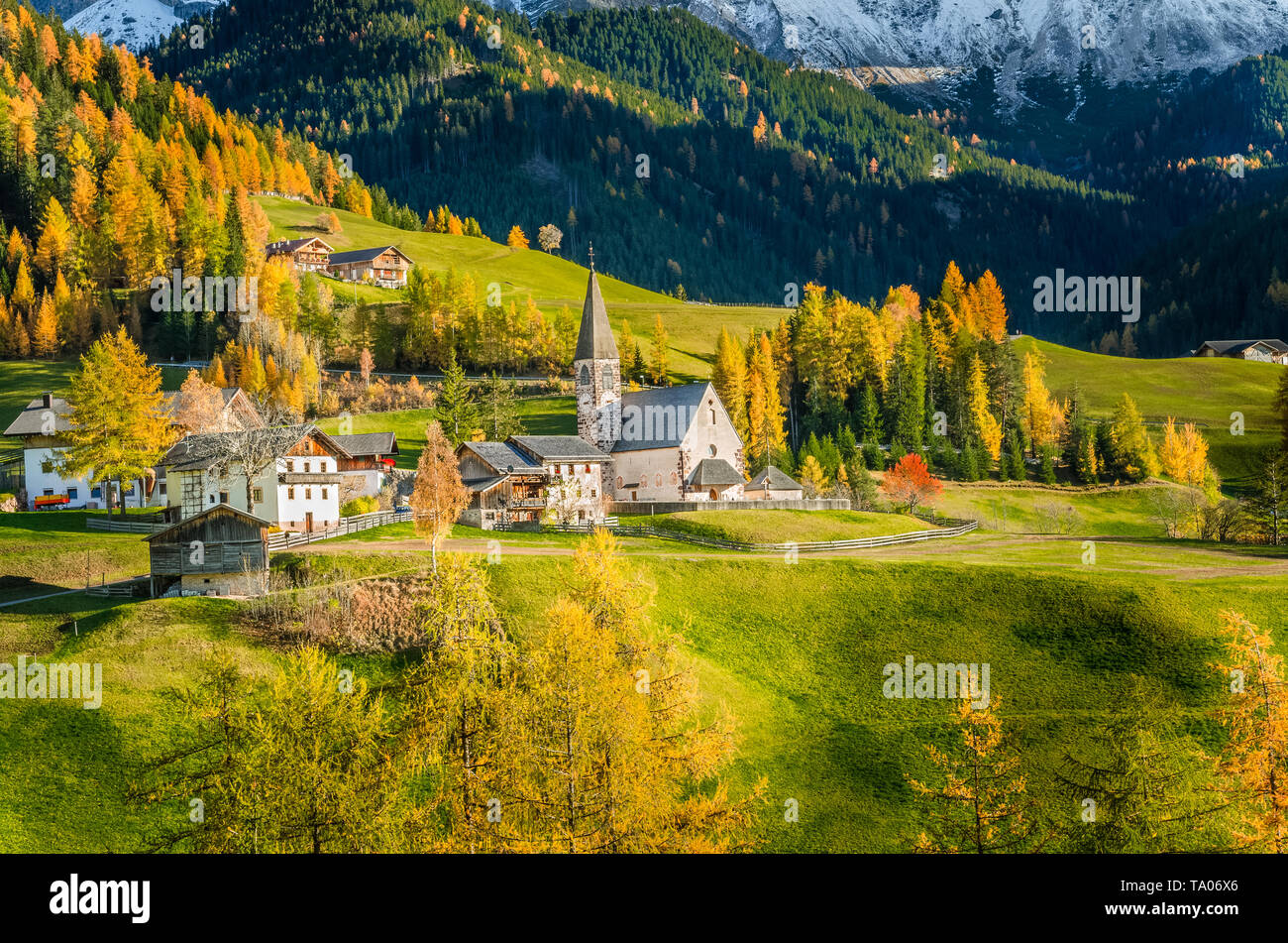 Traditional alpine village in the Dolomites warmly lit by a setting sun in  autumn Stock Photo - Alamy