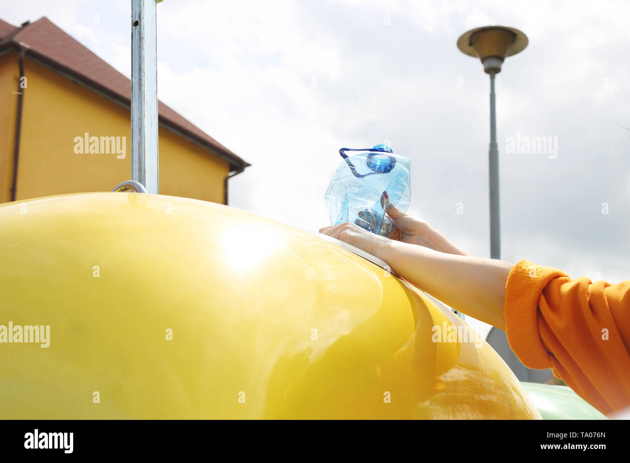 Recycling, a woman throws plastic waste into a yellow container Stock