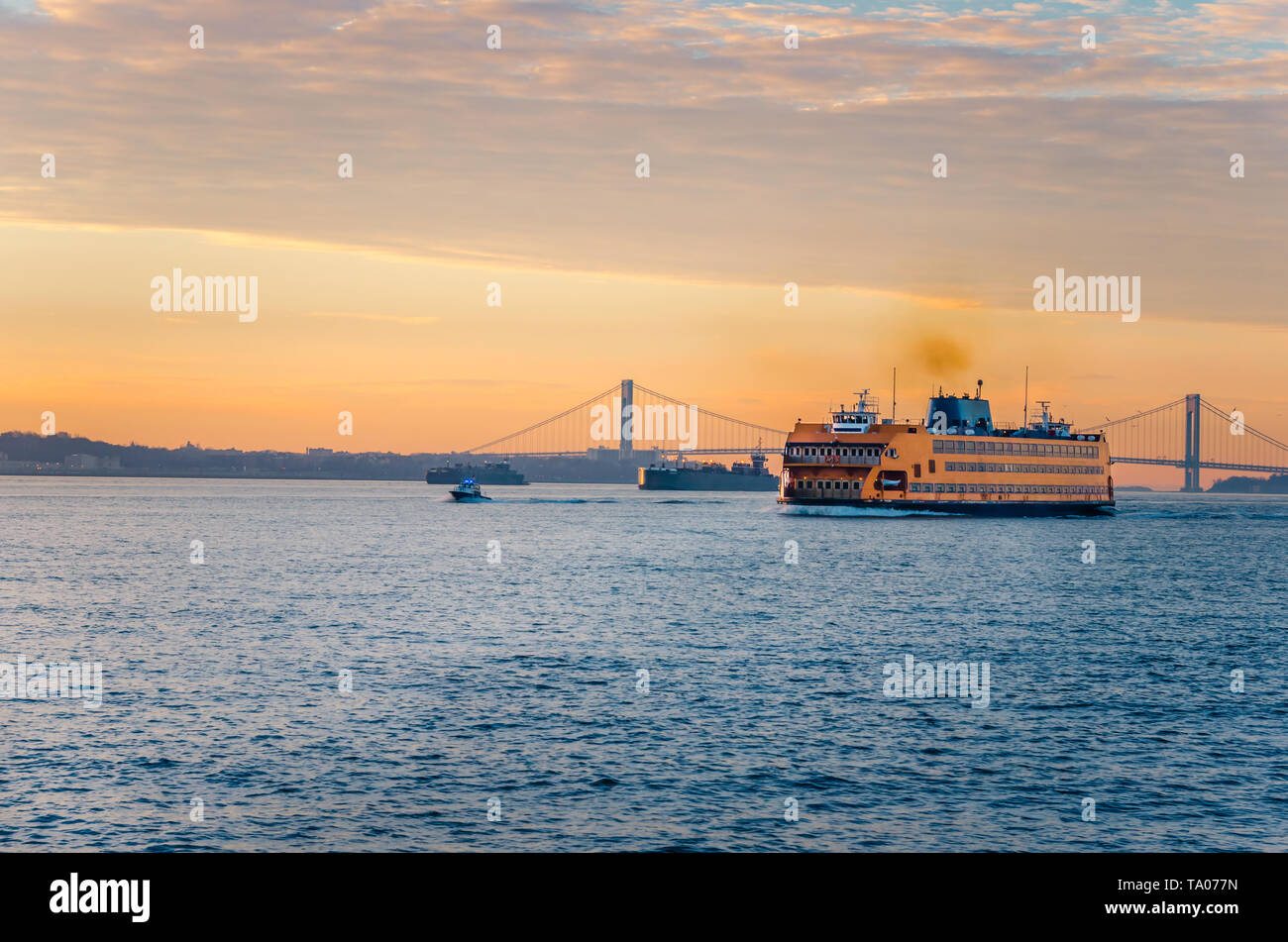View of Staten Island Ferry crossing New York bay at dawn on a winter day. Verrazano bridge is visible in background. Stock Photo