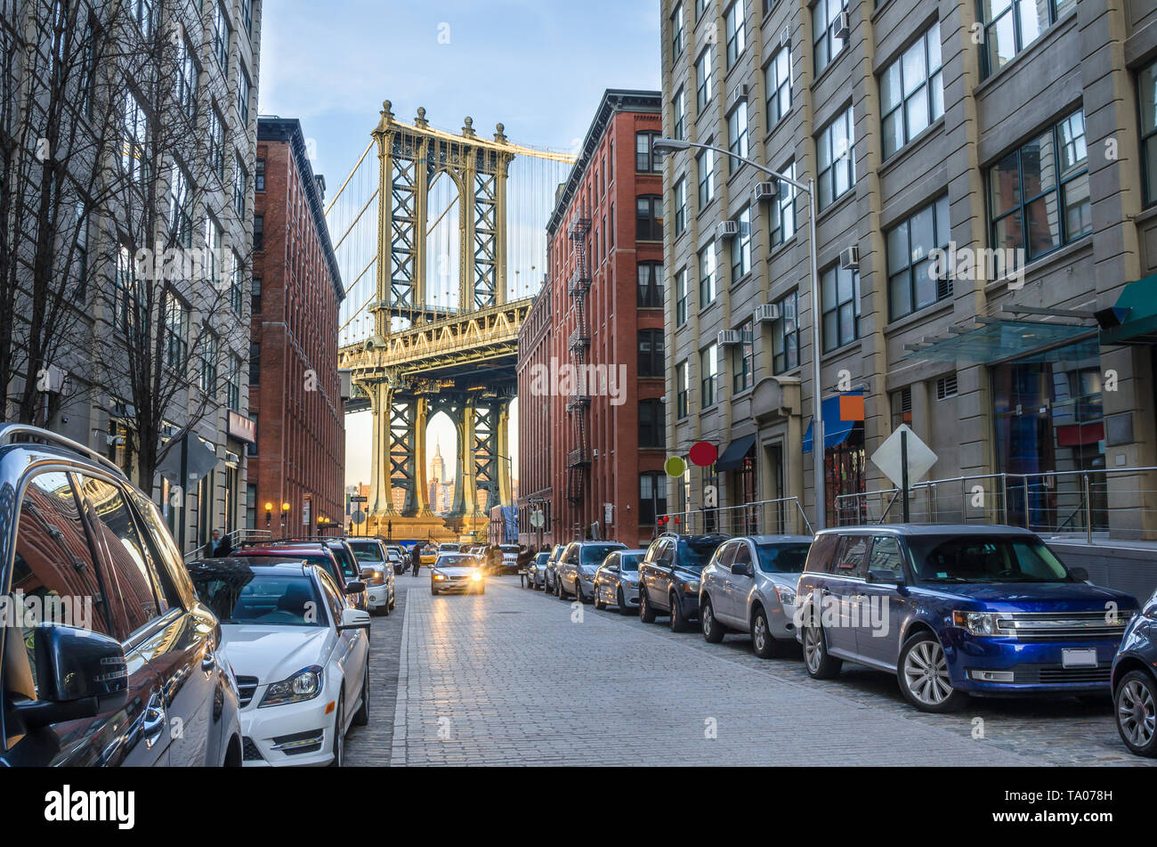 View of Manhattan Bridge form a narrow cobbled street in Brooklyn at sunset in winter. Stock Photo