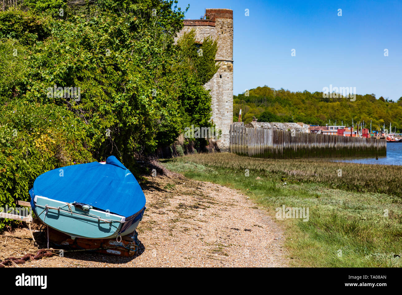 A blue wooden dinghy on the beach below Upnor Castle on the River Medway, Kent, UK Stock Photo