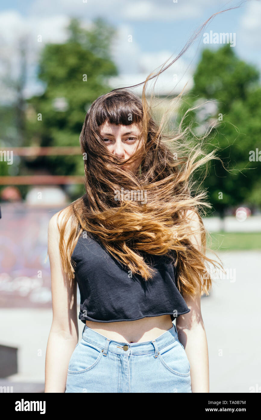 Woman standing outside with her long hair being blown across her face Stock Photo