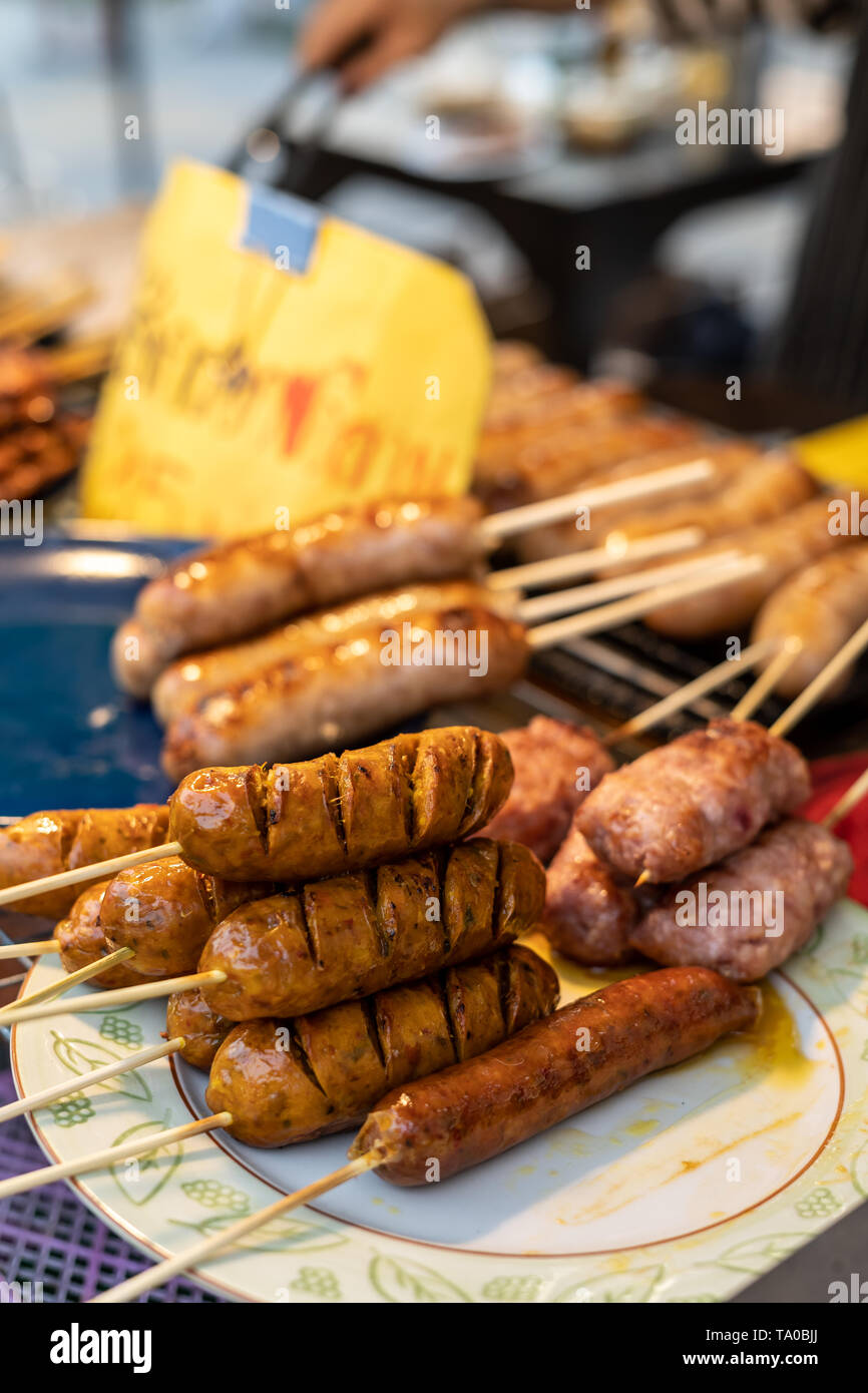 Sai Ua, the northen thai sausage on some wooden stick on a plate at a market in Chiang Mai, Thailand Stock Photo