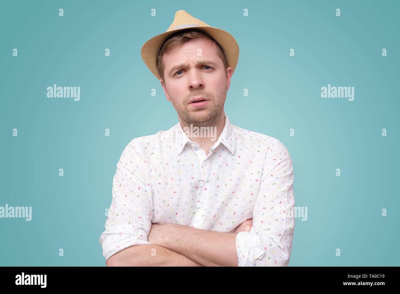 Young man in summer hat frowning showing disbelief or doubt. Stock Photo