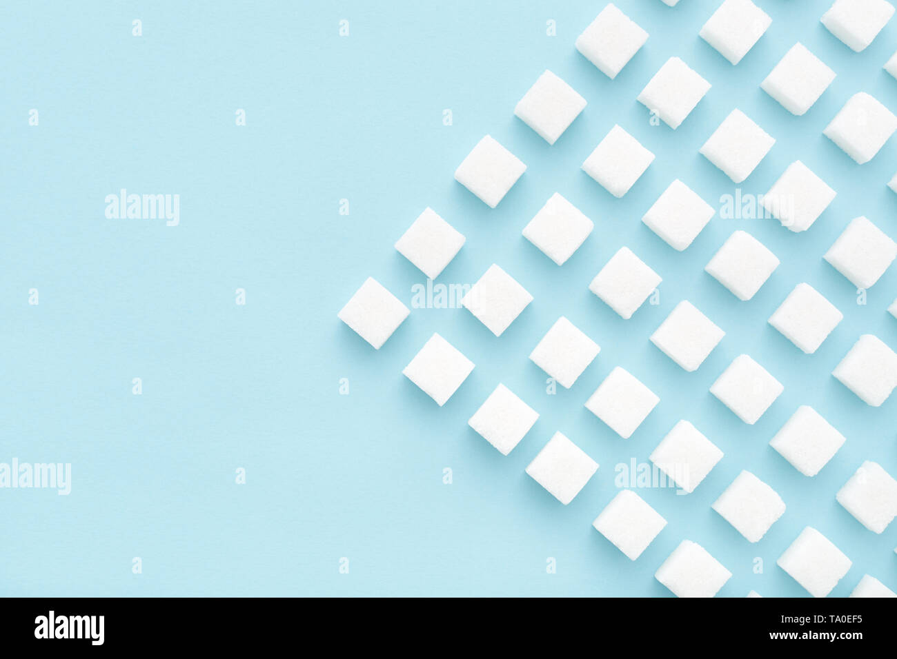 Sugar cubes abstract pattern on light blue background. Copy space, top view, minimal style. Ebergy concept. Stock Photo