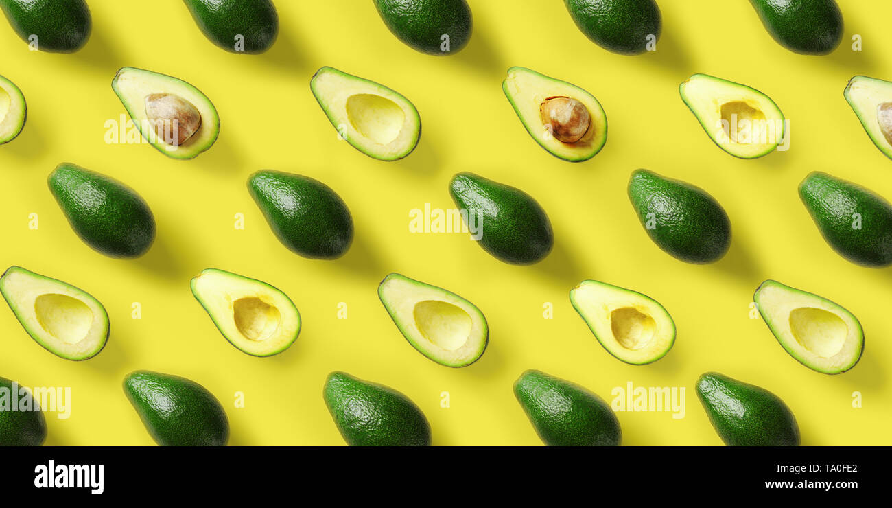 Avocado pattern on yellow background. Pop art design, creative summer food concept. Green avocadoes, minimal flat lay style. Top view Stock Photo
