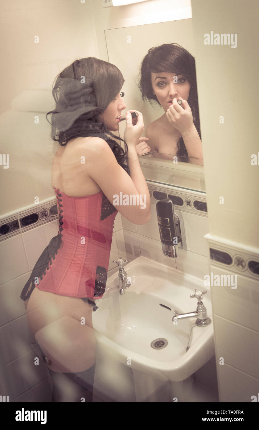 Young woman wearing sexy lingerie looking at herself in a bathroom mirror  Stock Photo