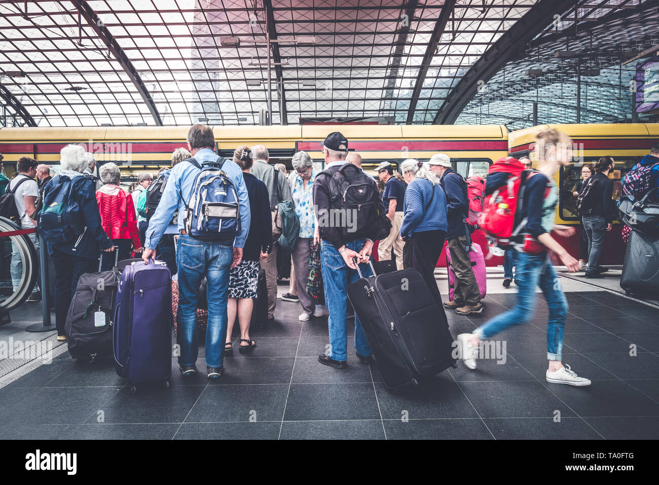 Berlin, Germany - May,  2019: Group of elder people with luggage at train station platform entering S-Bahn  train at Berlin Hauptnbahnhof Stock Photo