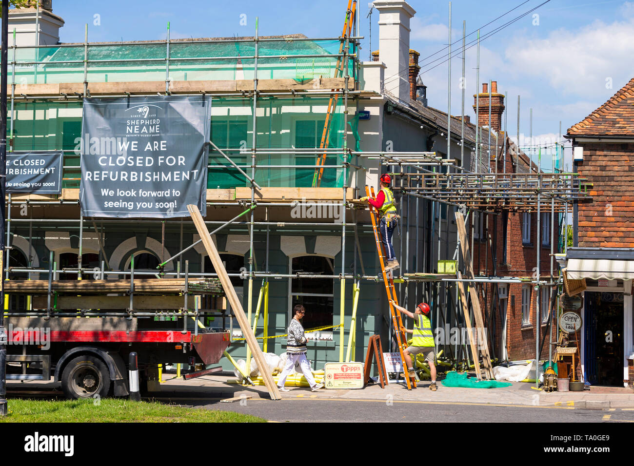 Shepherd neame pub closed for refurbishment, covered in scaffold with workers climbing a ladder, tenterden, kent, uk Stock Photo
