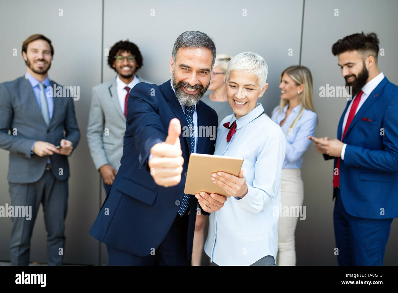 Portrait of thumb up smiling business people Stock Photo - Alamy